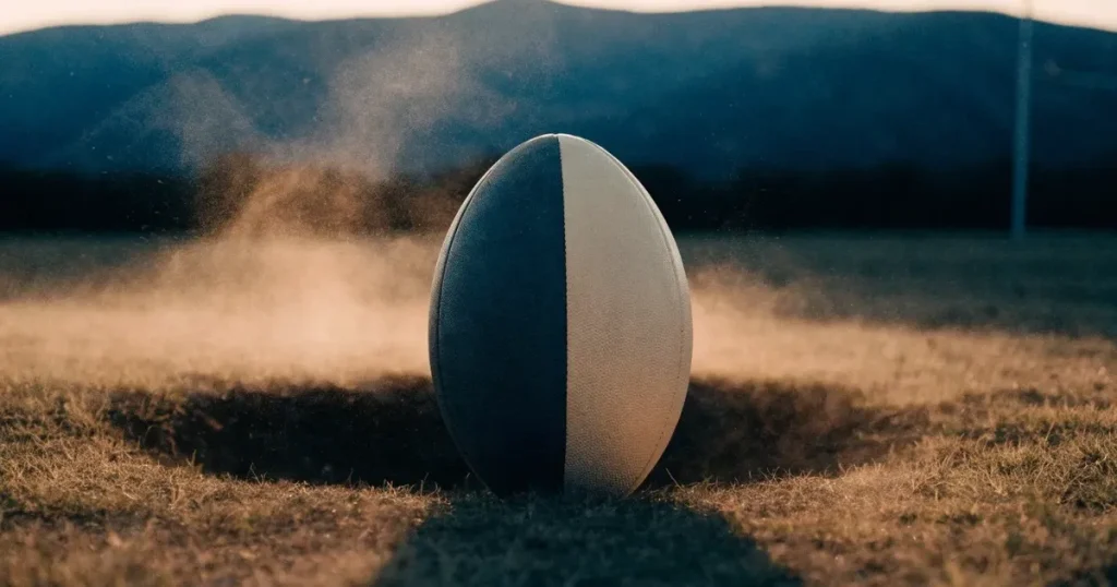 Ein Fussball auf einem staubigen Rasenstück in der Abendsonne, im Hintergrund eine hohe Bergkette